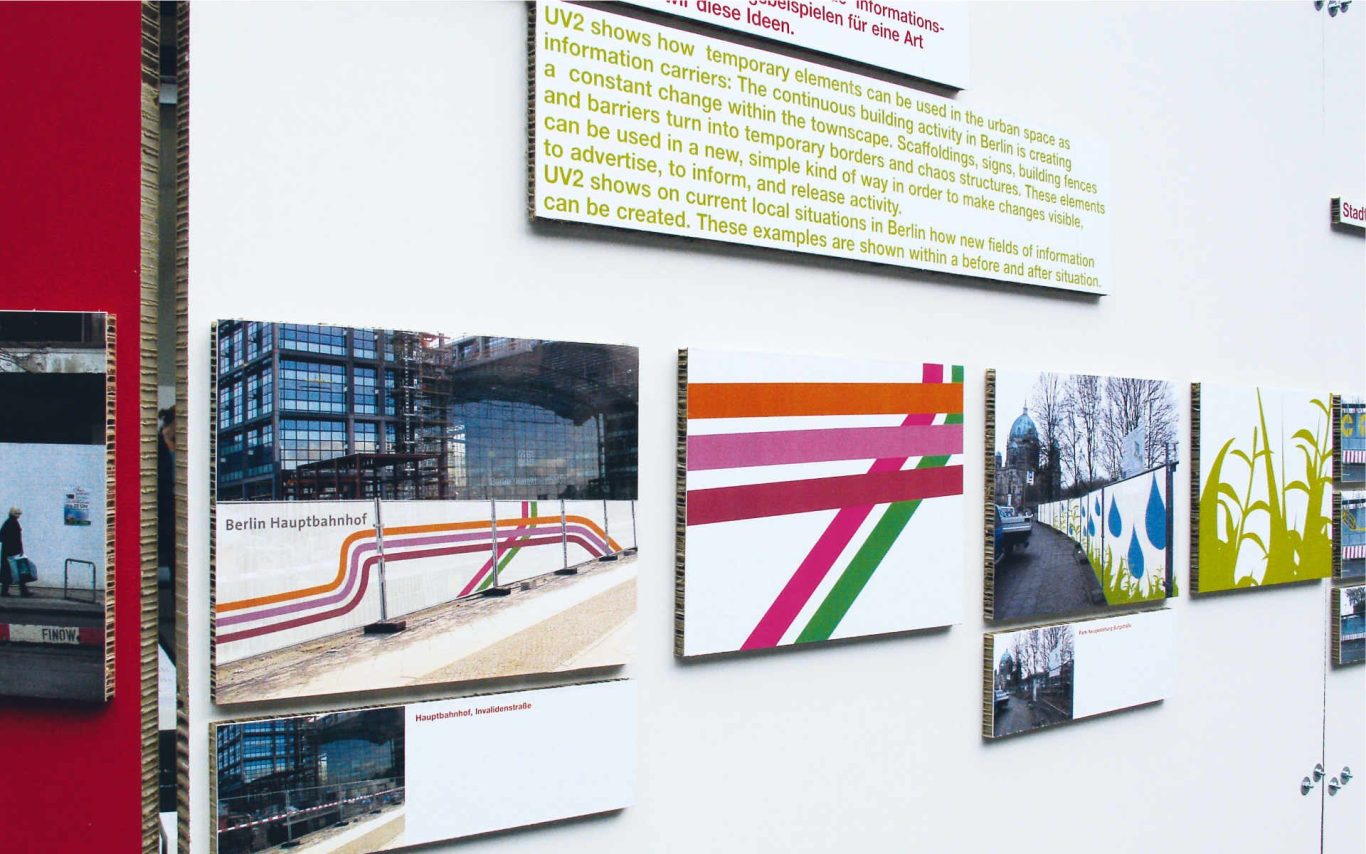 Karton-Informationstafel mit Fotografien und bunter Grafik.