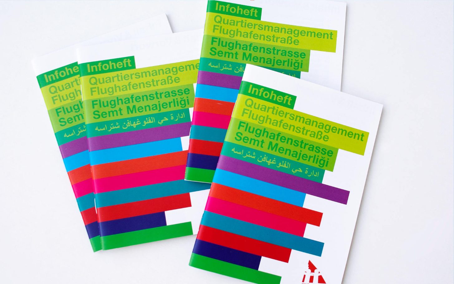 Drei Broschüren mit bunten, horizontalen Streifen auf dem Cover.