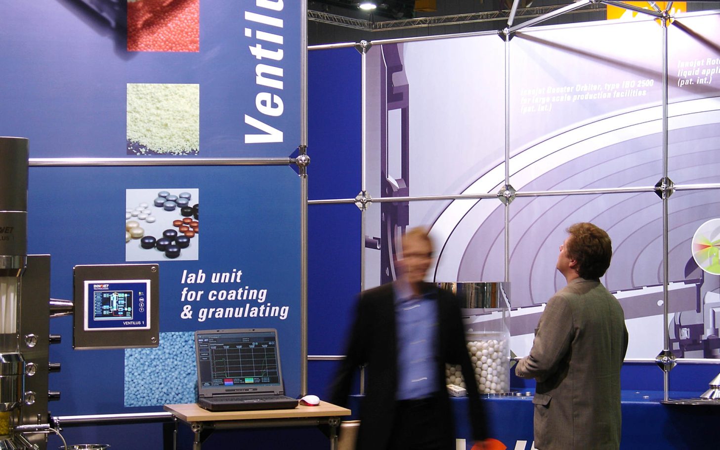 Messestand mit Informationen zu Ventilation und zwei Personen im Gespräch.