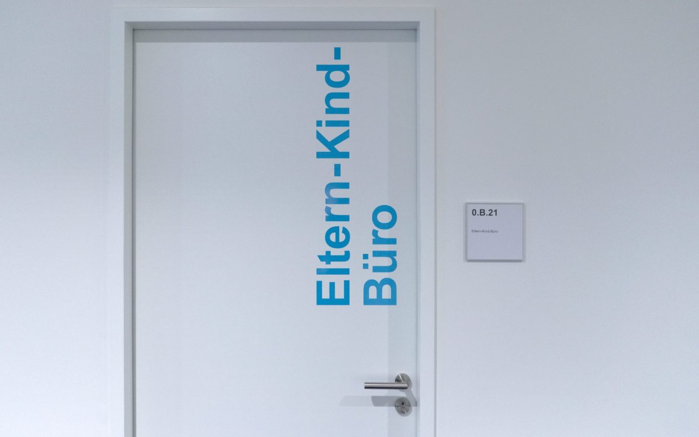 Tür zum Eltern-Kind-Raum mit blauer Beschriftung.
