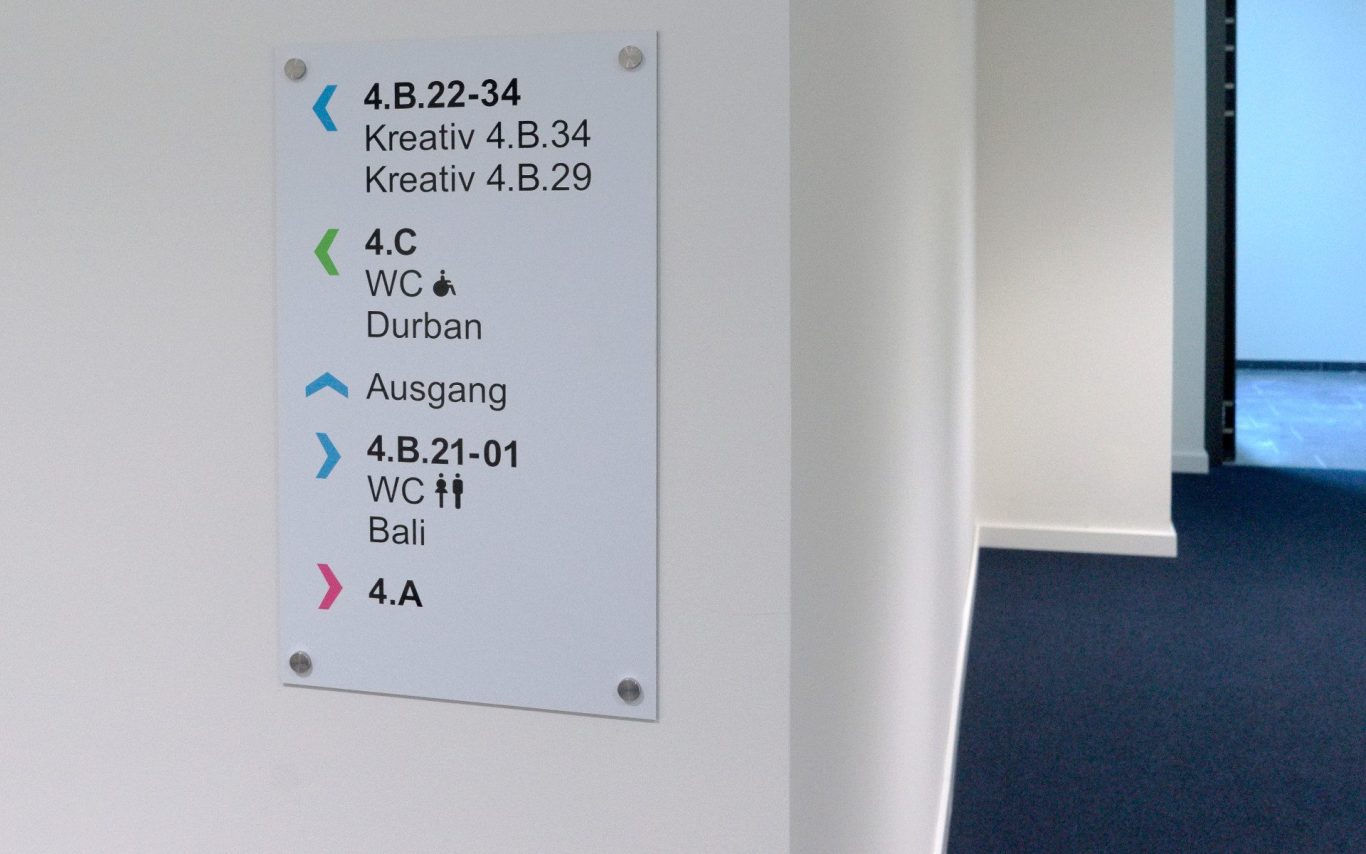 Wandbeschilderung mit Raumnummern und Richtungsangaben in Büroflur.