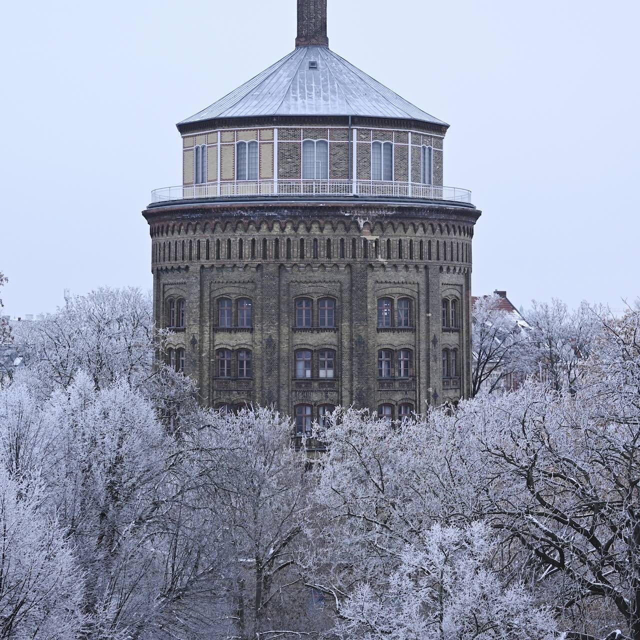 Historisches Wasserturm umgeben von verschneiten Bäumen im Winter.